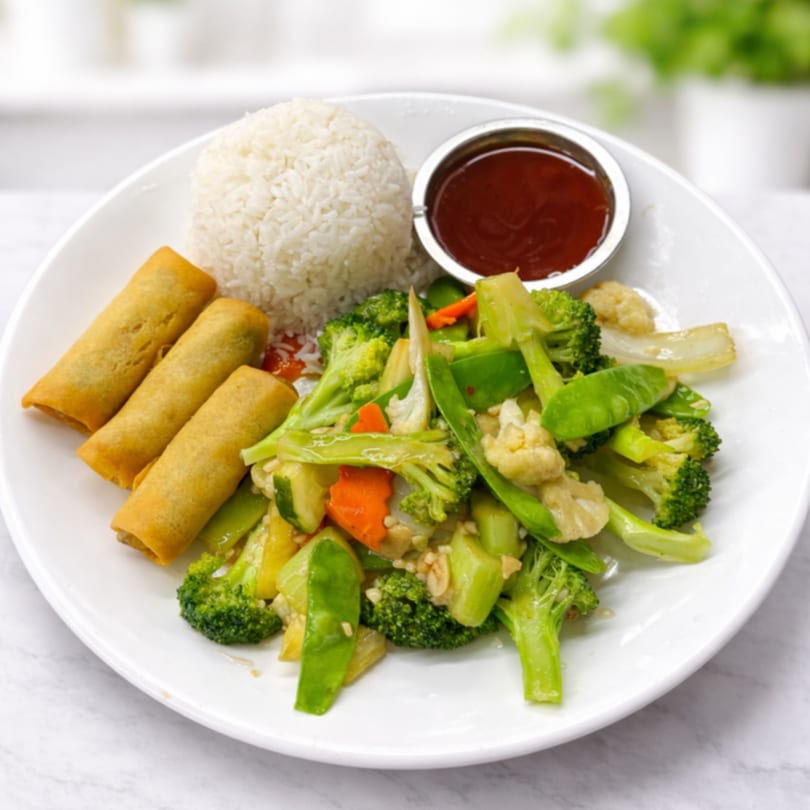 A white plate with rice, three egg rolls, stir-fried vegetables, and a side of sauce.