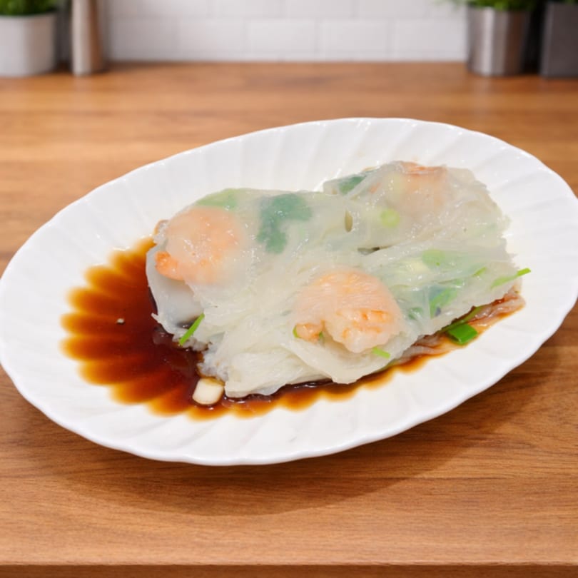 Shrimp rice rolls with green onions and soy sauce on a white plate on a wooden table.